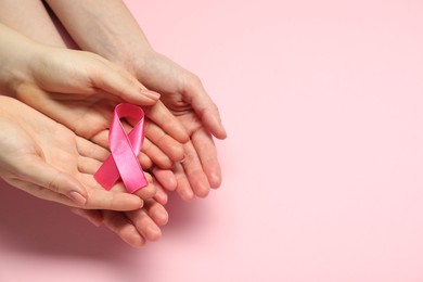 Photo of Breast cancer awareness. Women holding pink ribbon on color background, top view. Space for text