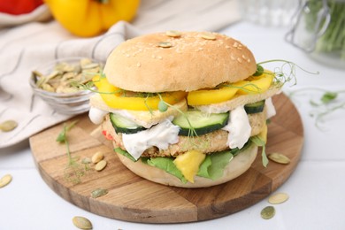 Photo of Tasty vegan burger with vegetables, sauce and patty on white table, closeup