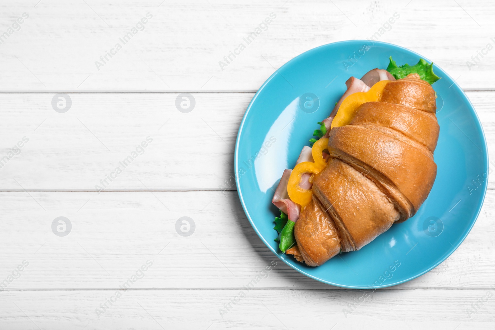 Photo of Tasty croissant sandwich with ham on white wooden table, top view. Space for text