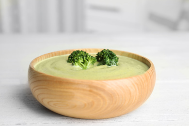 Photo of Delicious broccoli cream soup served on white wooden table