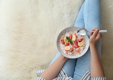 Photo of Woman eating delicious oatmeal with fruits at home, top view. Healthy diet