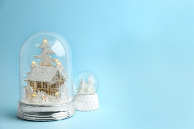 Photo of Beautiful snow globes on light blue background, space for text