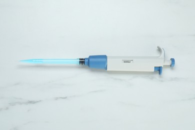 Photo of Laboratory analysis. Micropipette with liquid on white marble table, top view