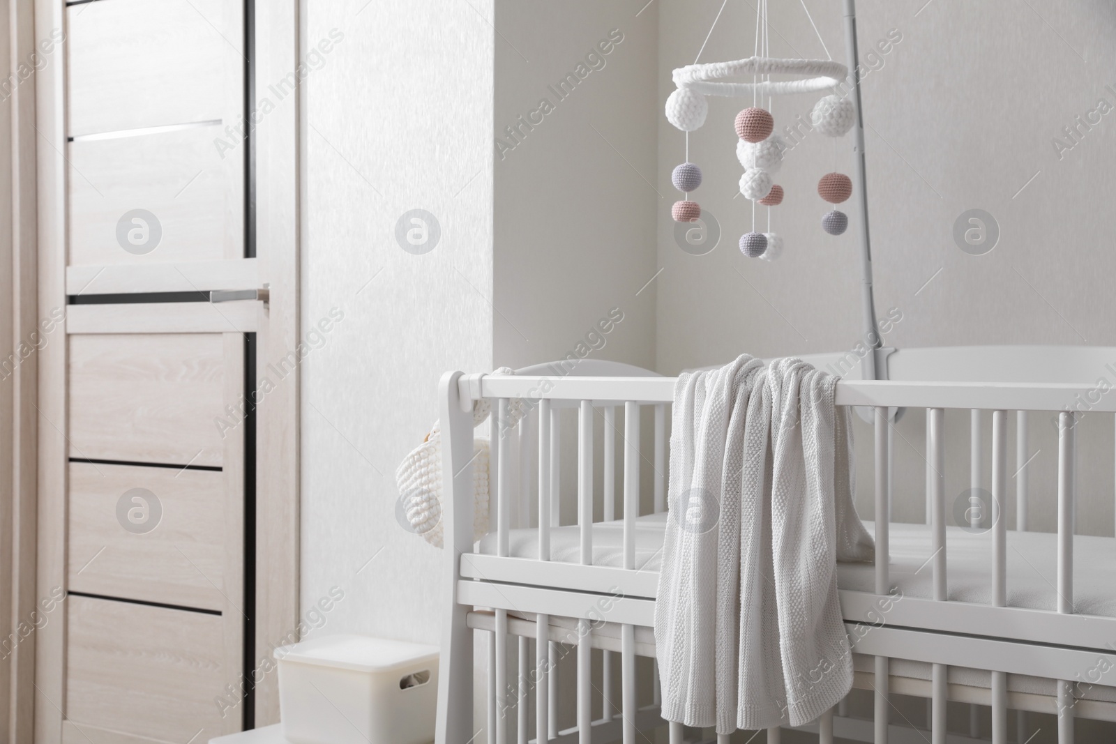 Modern crib with baby mobile in children's room. Interior design Photo of Modern crib with baby mobile in children's room. Interior design