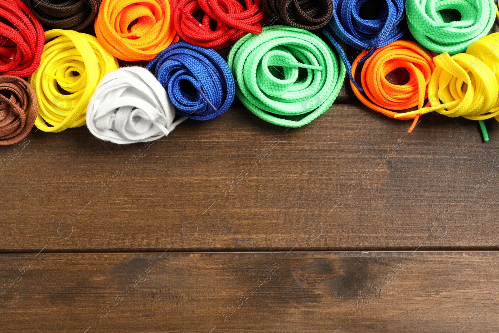 Photo of Colorful shoelaces on wooden background, flat lay. Space for text