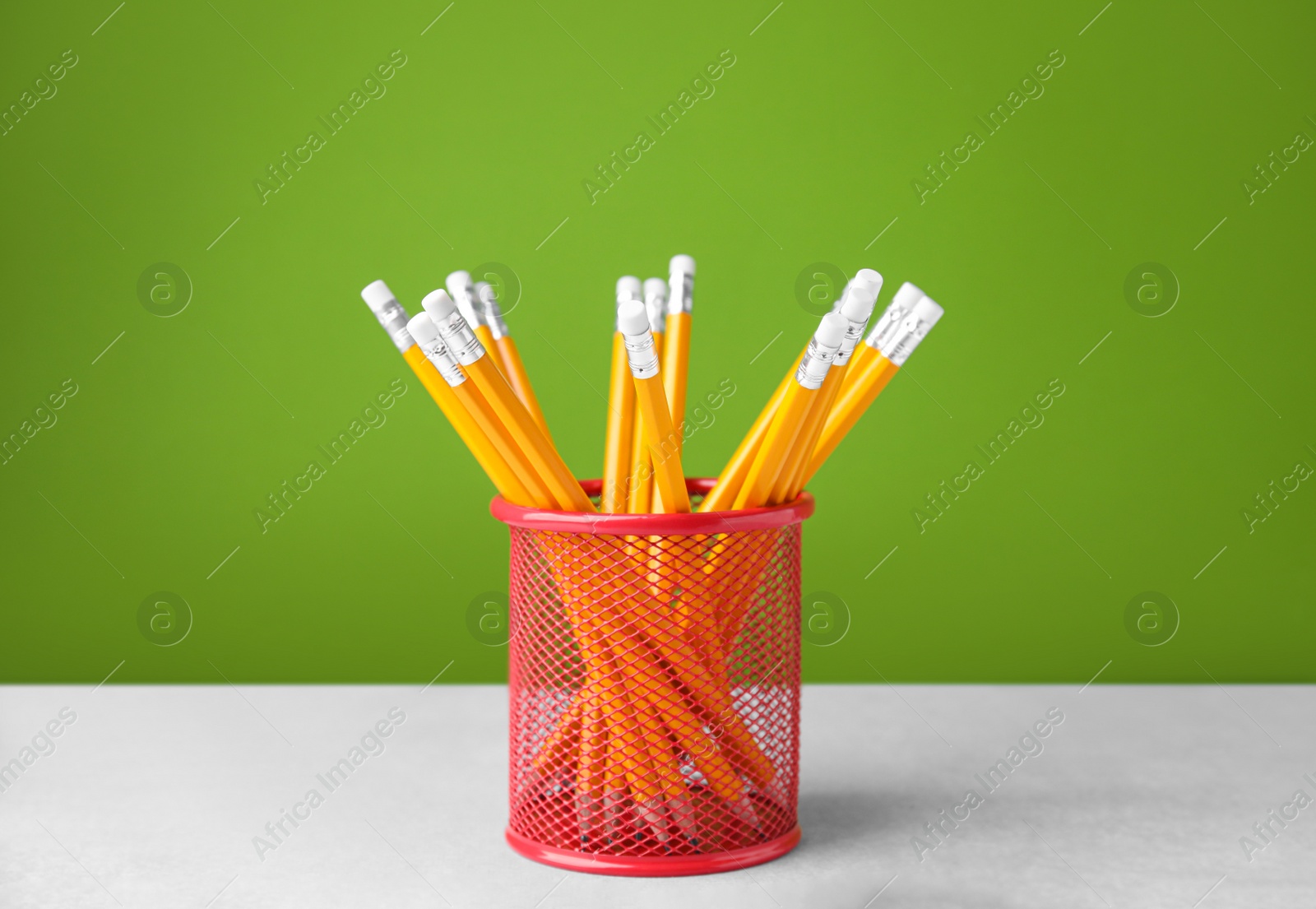 Photo of Many sharp pencils in holder on light table against green background