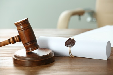 Photo of Gavel and scroll with notary seal on wooden table in office