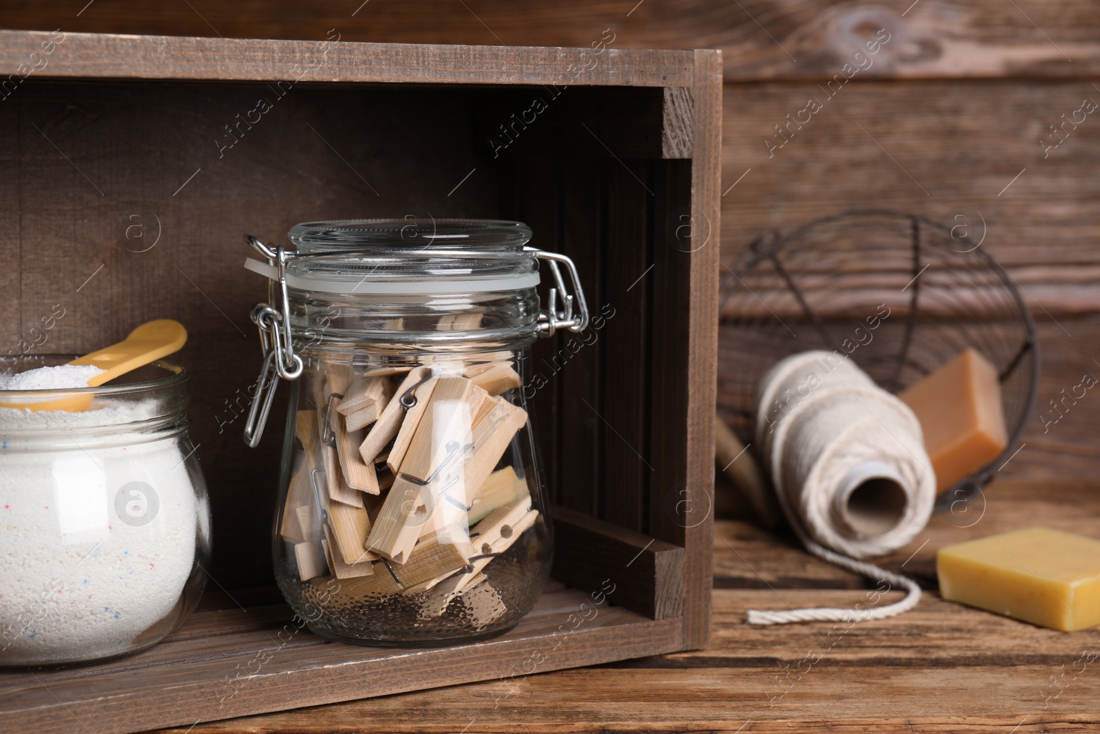 Photo of Wooden clothespins in glass jar and detergent powder on table