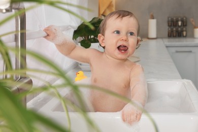 Photo of Cute little baby bathing in sink at home