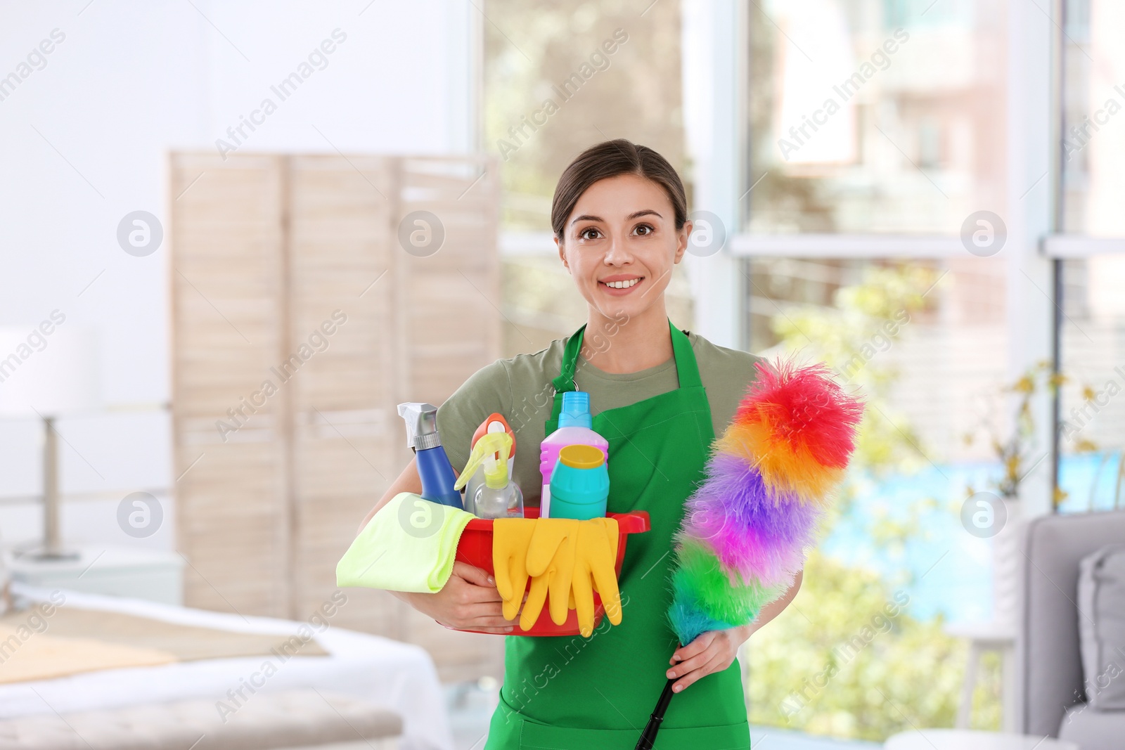 Photo of Woman in uniform with cleaning supplies indoors