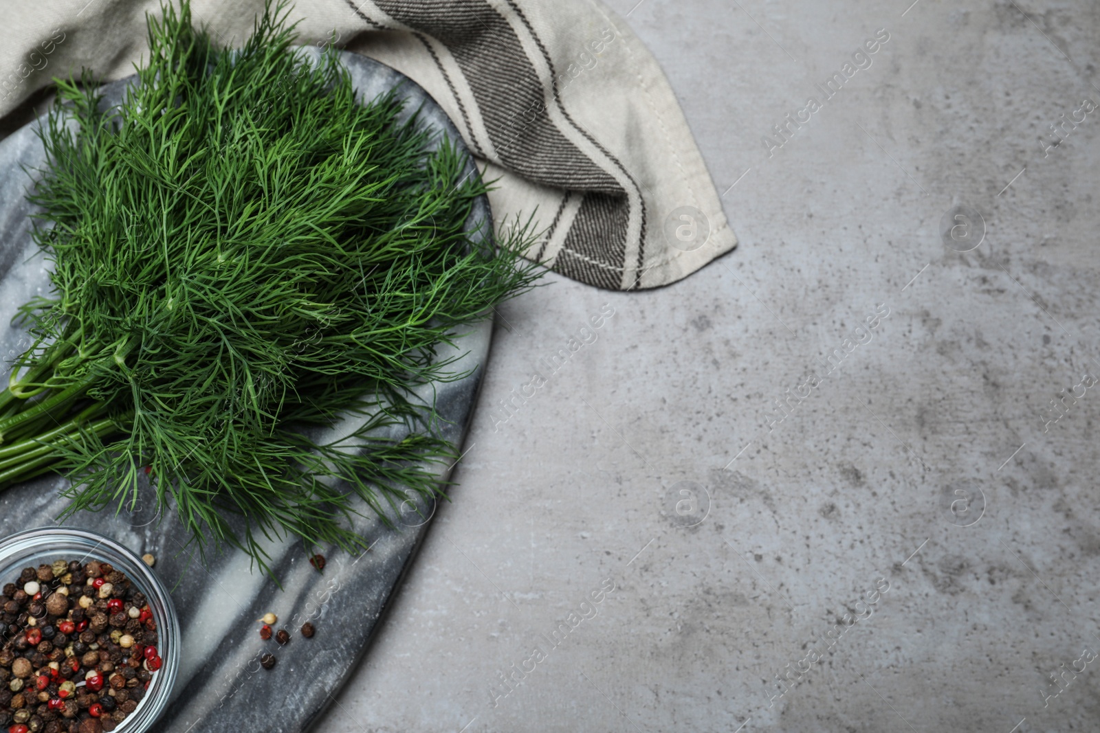 Photo of Marble board with fresh green dill and spices on grey table, flat lay. Space for text