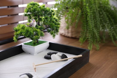 Photo of Beautiful miniature zen garden on wooden table, closeup