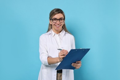 Portrait of happy doctor with clipboard on light blue background