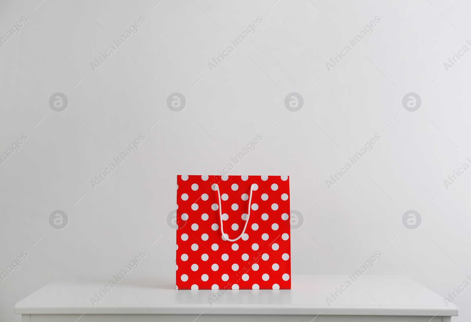 Photo of Paper shopping bag on white table against light background