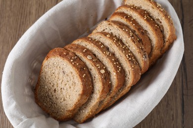 Photo of Slices of fresh bread in basket on wooden table, above view