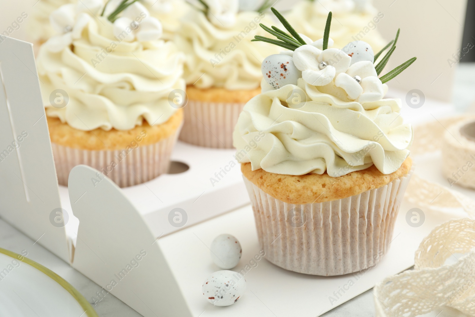 Photo of Tasty Easter cupcakes with vanilla cream on table, closeup