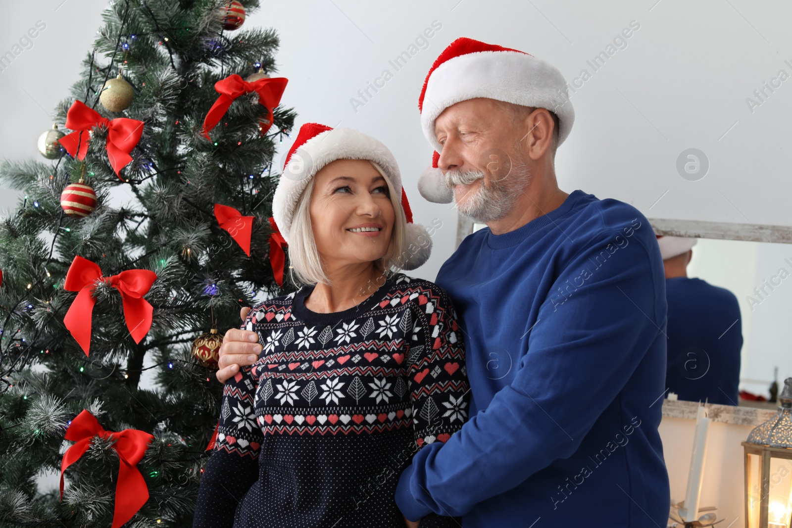 Photo of Mature couple in Santa hats at home. Christmas celebration