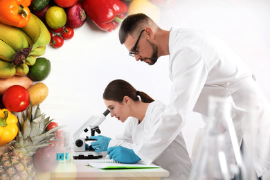 Scientist with microscope at table and her colleague in laboratory. Food quality analysis