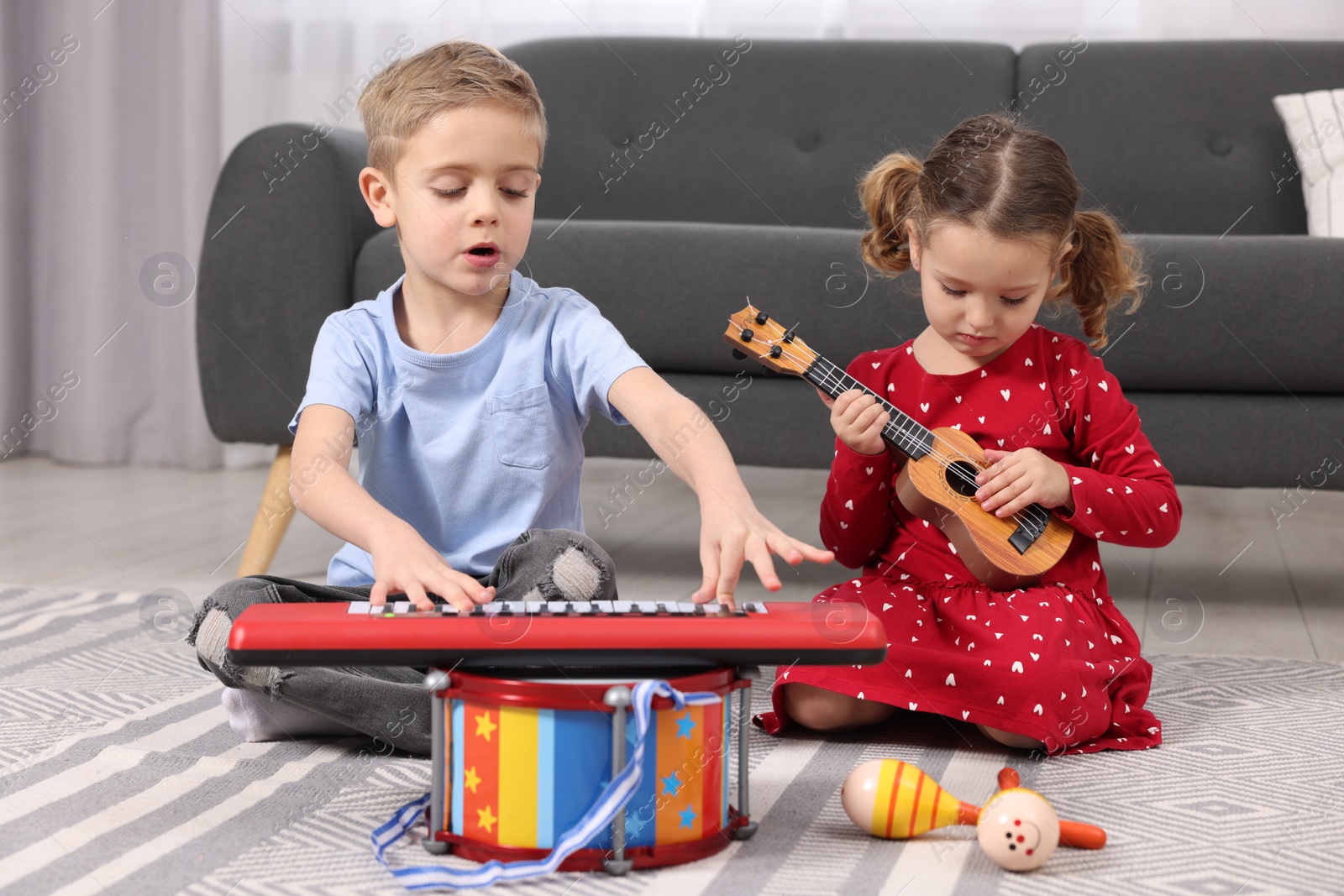 Photo of Little children playing toy musical instruments at home