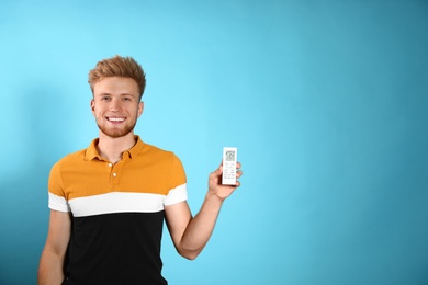 Photo of Young man with air conditioner remote on blue background. Space for text