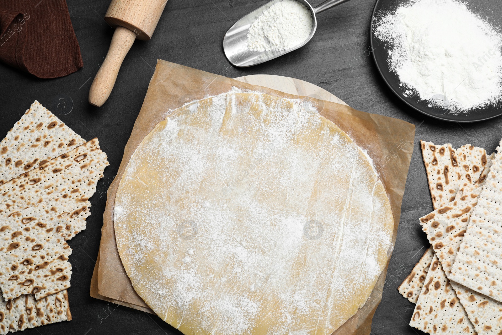 Photo of Matzos and raw dough on black table, flat lay