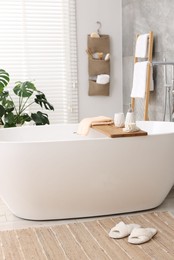 Set of different bath accessories and soap on tub in bathroom