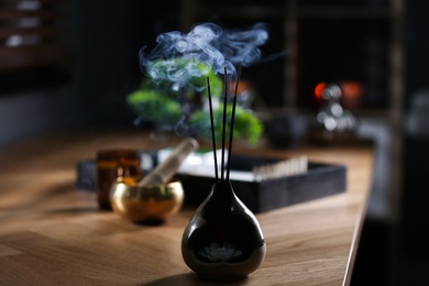 Incense sticks smoldering on wooden table indoors