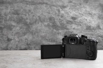 Photo of Modern camera on light grey stone table, space for text. Video production industry