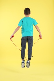Photo of Active boy jumping rope on color background