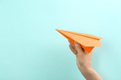 Photo of Woman holding paper plane on light blue background, closeup. Space for text