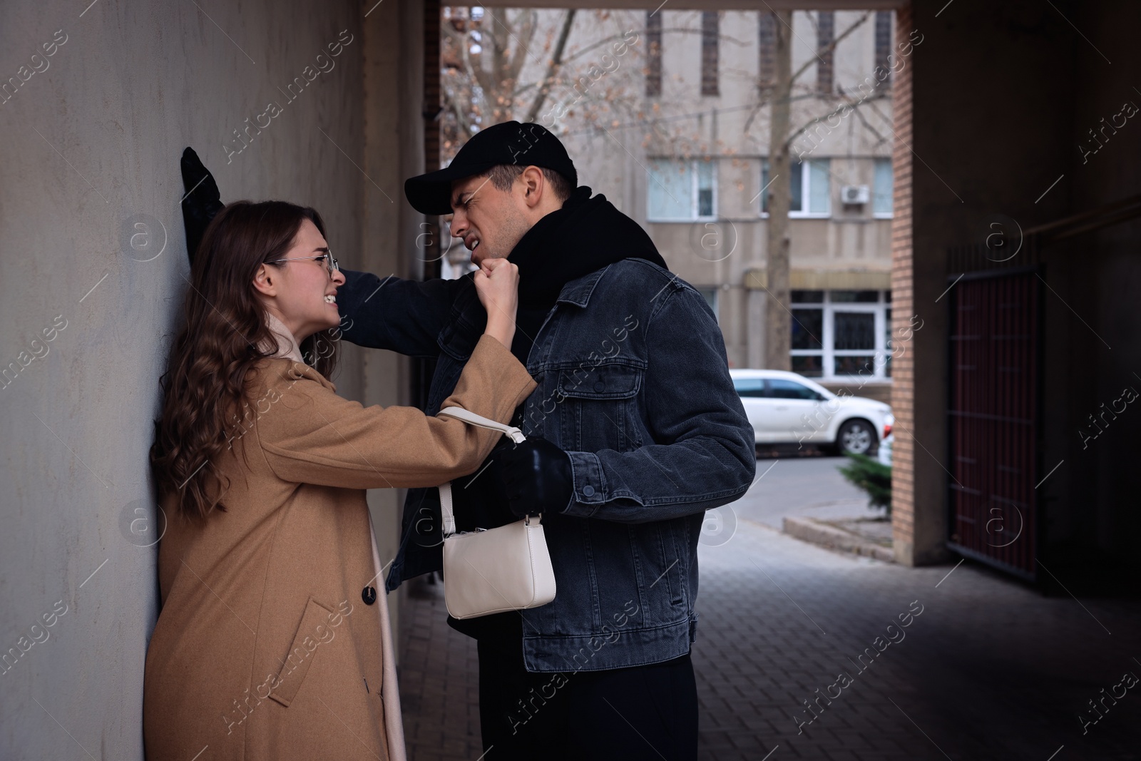 Photo of Woman fighting with thief while he trying to steal her bag in alley. Self defense concept