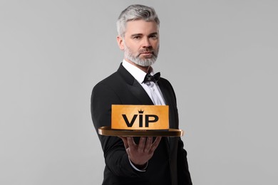 Photo of Handsome man holding tray with VIP sign on light grey background