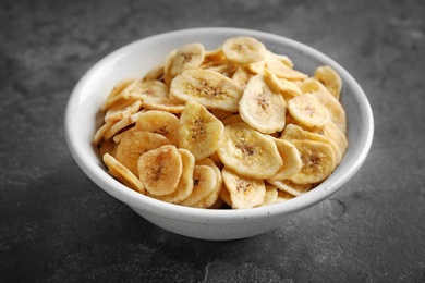 Photo of Bowl with sweet banana slices on grey background. Dried fruit as healthy snack