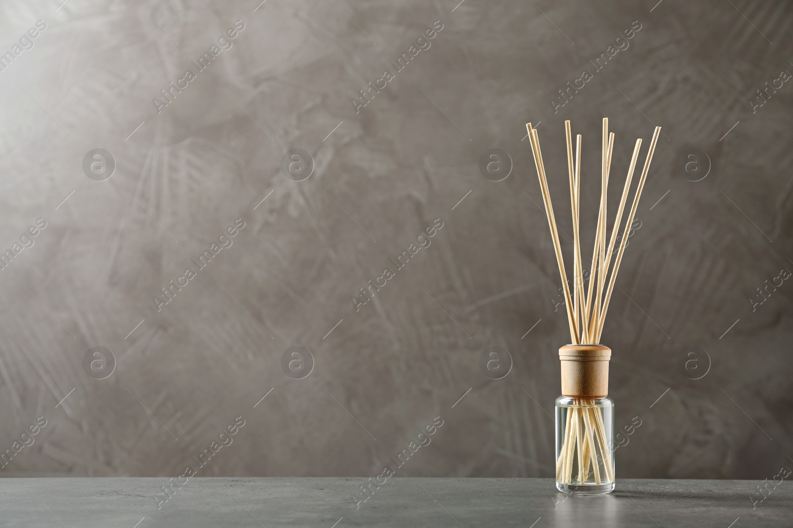 Photo of Reed air freshener on table against brown background, space for text