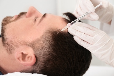 Photo of Man with hair loss problem receiving injection in salon