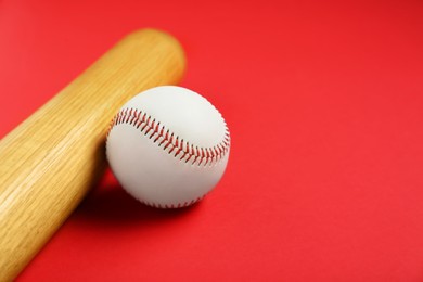 Photo of Wooden baseball bat and ball on red background, closeup. Space for text