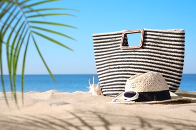 Stylish beach accessories on sand near sea