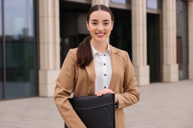 Photo of Female real estate agent with leather portfolio outdoors