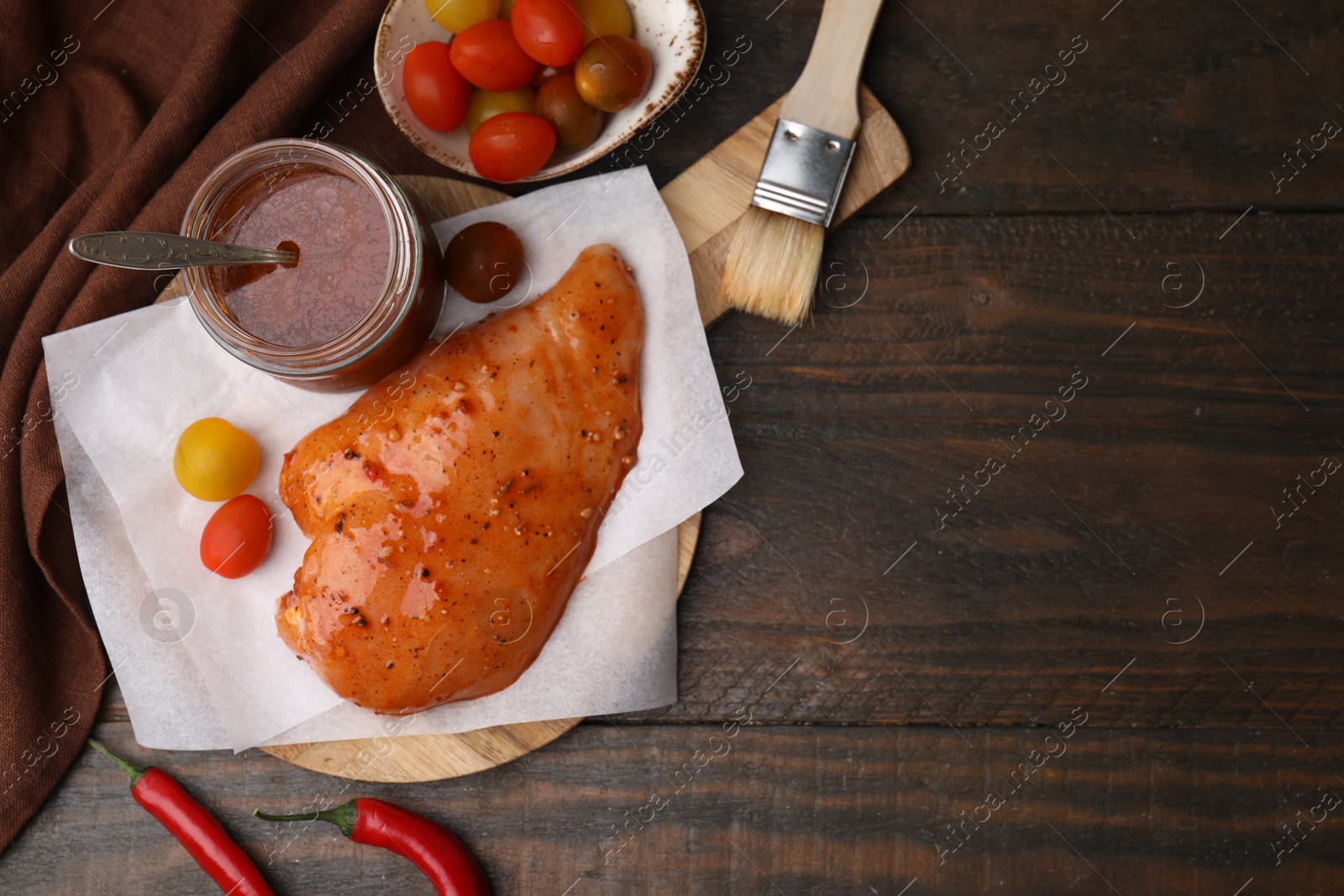 Photo of Fresh marinade and raw chicken fillets on wooden table, flat lay. Space for text