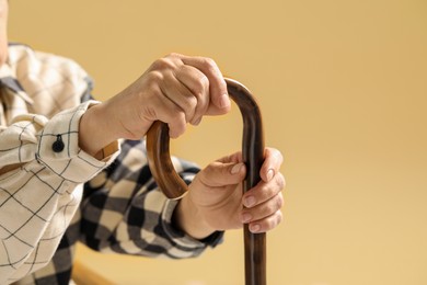 Photo of Elderly woman with walking cane on beige background, closeup. Space for text