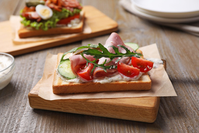Photo of Tasty sandwich with ham served on wooden table