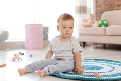 Photo of Adorable little baby playing with wooden blocks at home