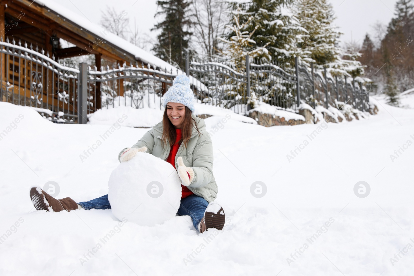 Photo of Happy woman making ball for snowman outdoors. Winter vacation