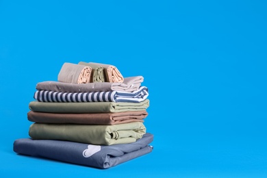 Photo of Stack of clean bed sheets on blue background. Space for text