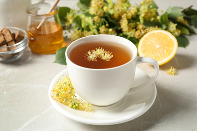 Cup of tea with linden blossom on light grey marble table