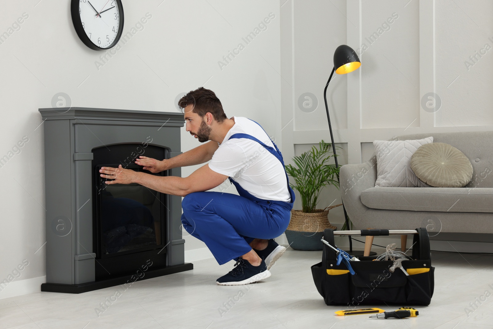 Photo of Professional technician installing electric fireplace in room