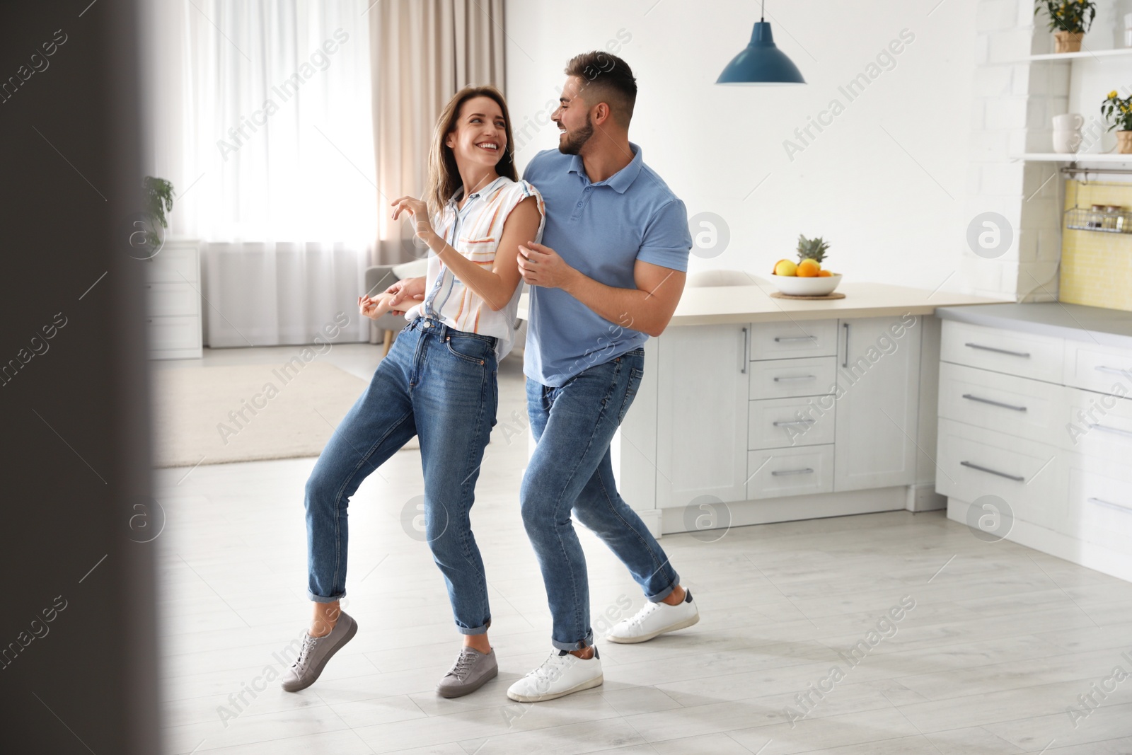 Photo of Lovely young couple dancing in kitchen at home