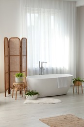 Photo of White tub near window in light room. Interior design