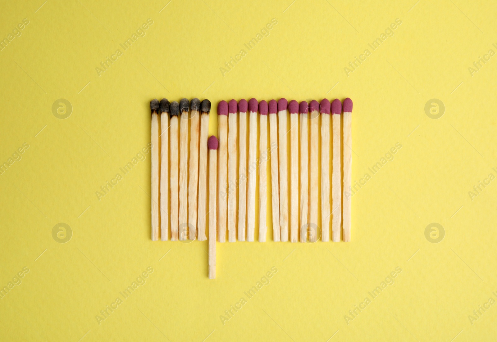 Photo of Flat lay composition with burnt and whole matches on yellow background