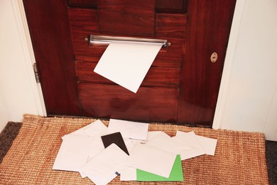 Photo of Wooden door with mail slot and many envelopes indoors